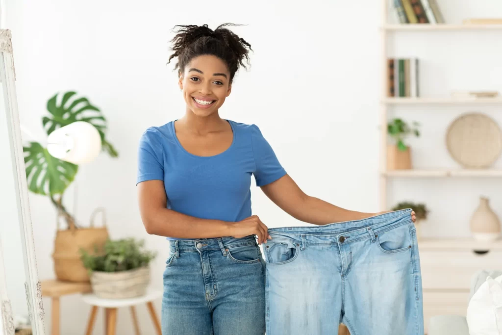 happy slim black woman showing old jeans standing utc
